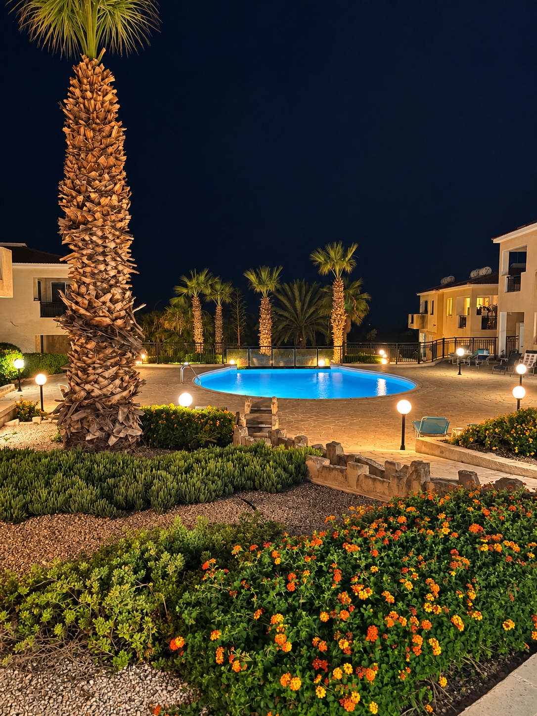 Illuminated swimming pool and landscaped gardens at Tala Riviera at night
